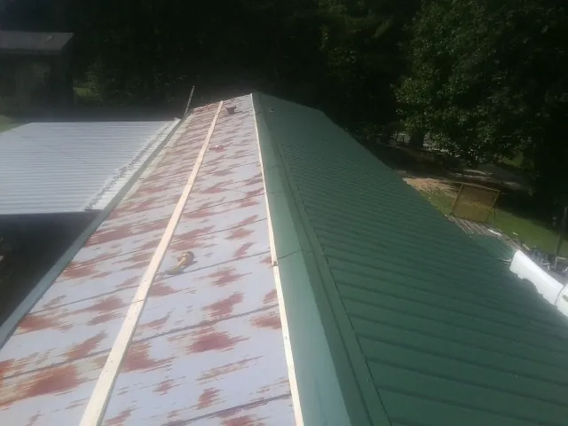 Old rusted panels beside newly installed green metal roofing — Wind Damage Roof Repair by Roofing Brothers in Greenwood
