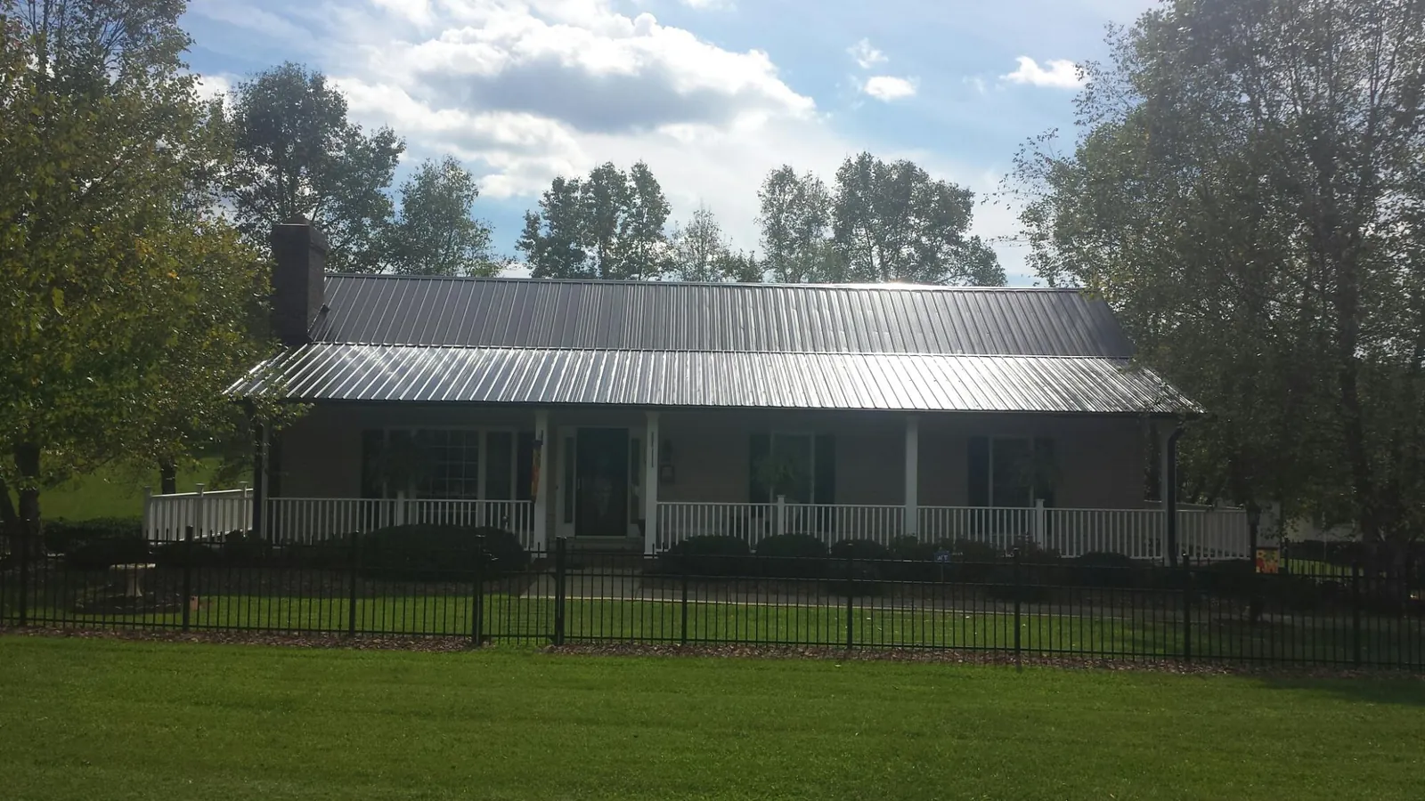 Gray metal roof on a brick ranch with a full width front porch — Gutter Guard Installation work by our crew in Greenwood